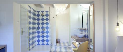 Un baño moderno con piso a cuadros, cabina de ducha de vidrio y tocador con lavabo.