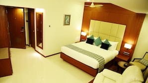 Habitación de hotel con una cama grande, una zona de estar con una silla y una pequeña mesa.