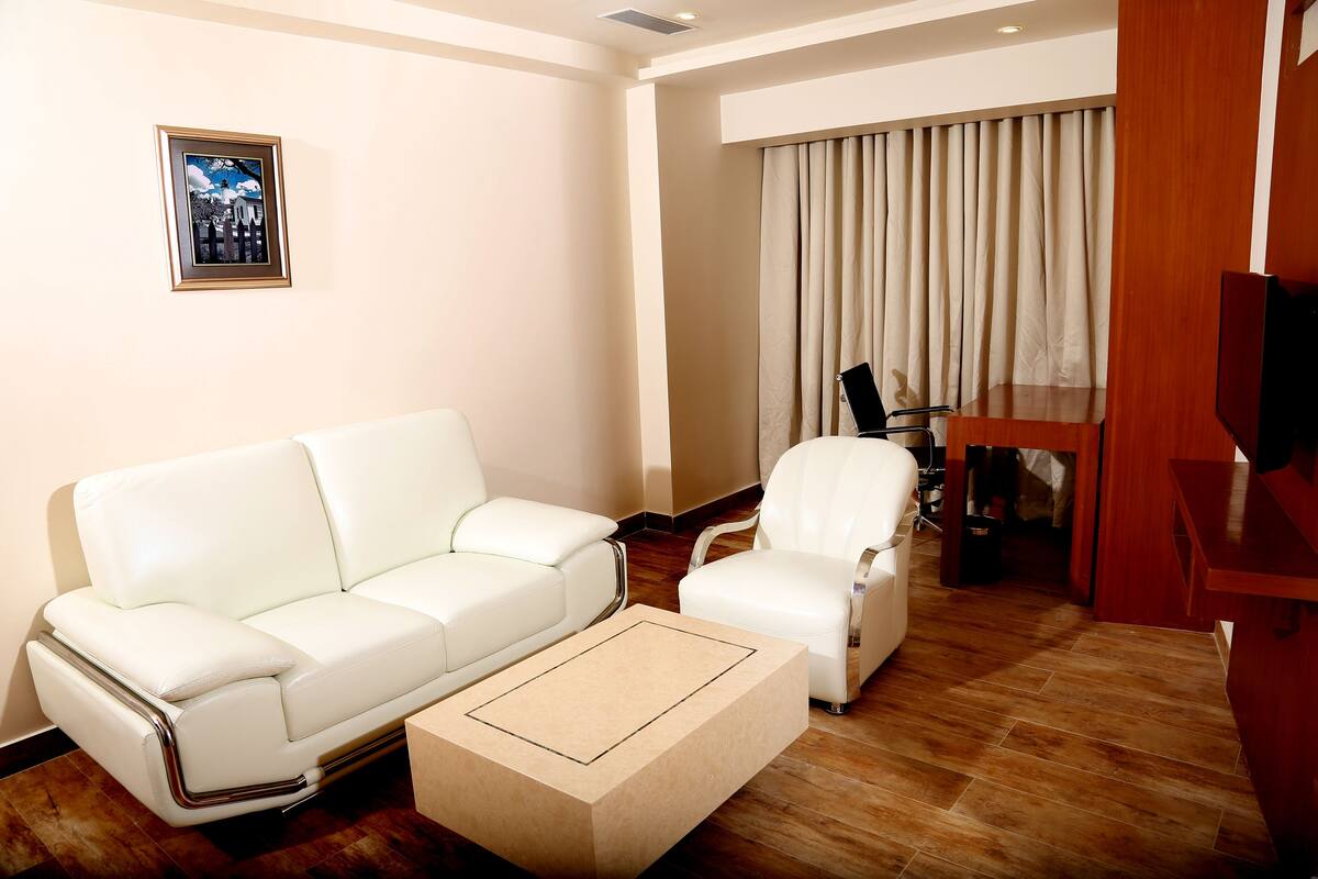 A living room with a white leather sofa, a white armchair, and a wooden coffee table.