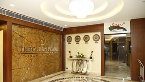Un vestíbulo con piso de mármol, una recepción y un letrero del hotel 'The Ocean Pearl'.