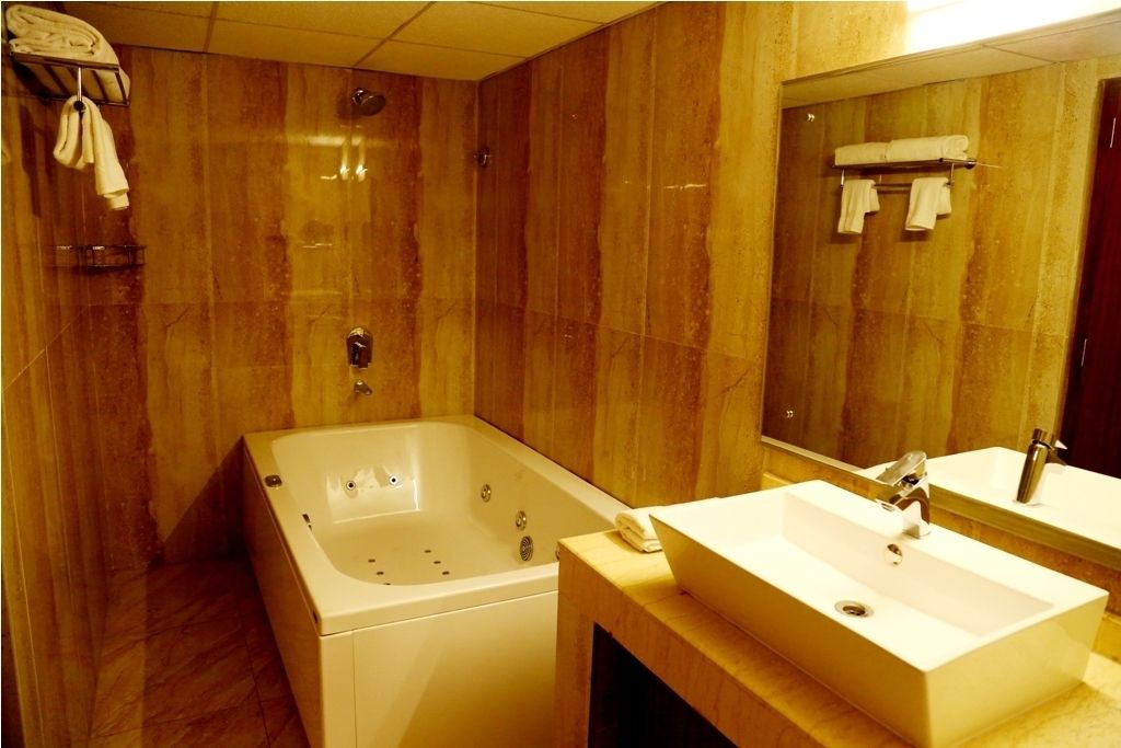 Un bany amb una banyera gran, un lavabo i un mirall.