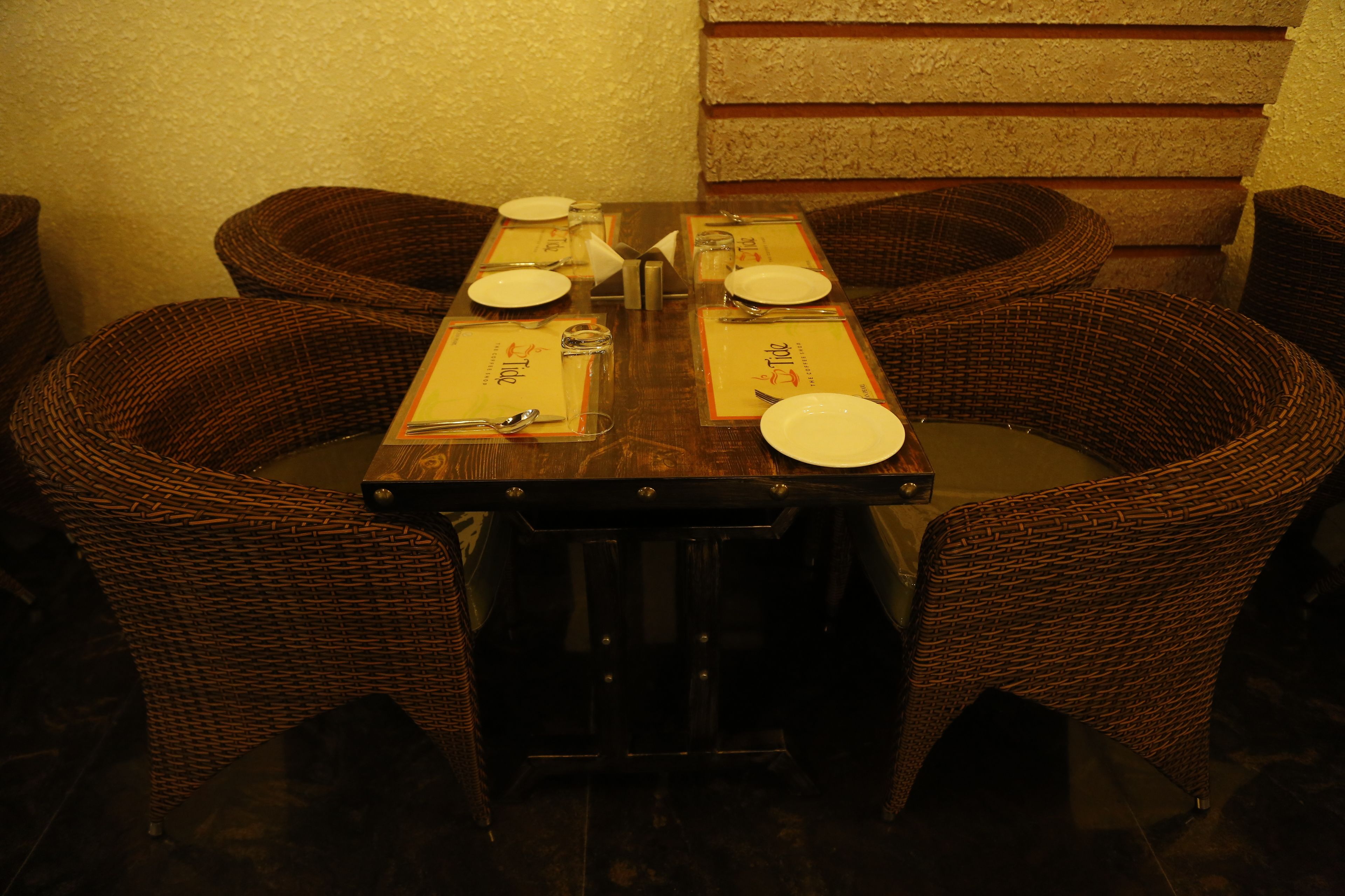 A dining table set for four with wicker chairs, a wooden table, and a menu.