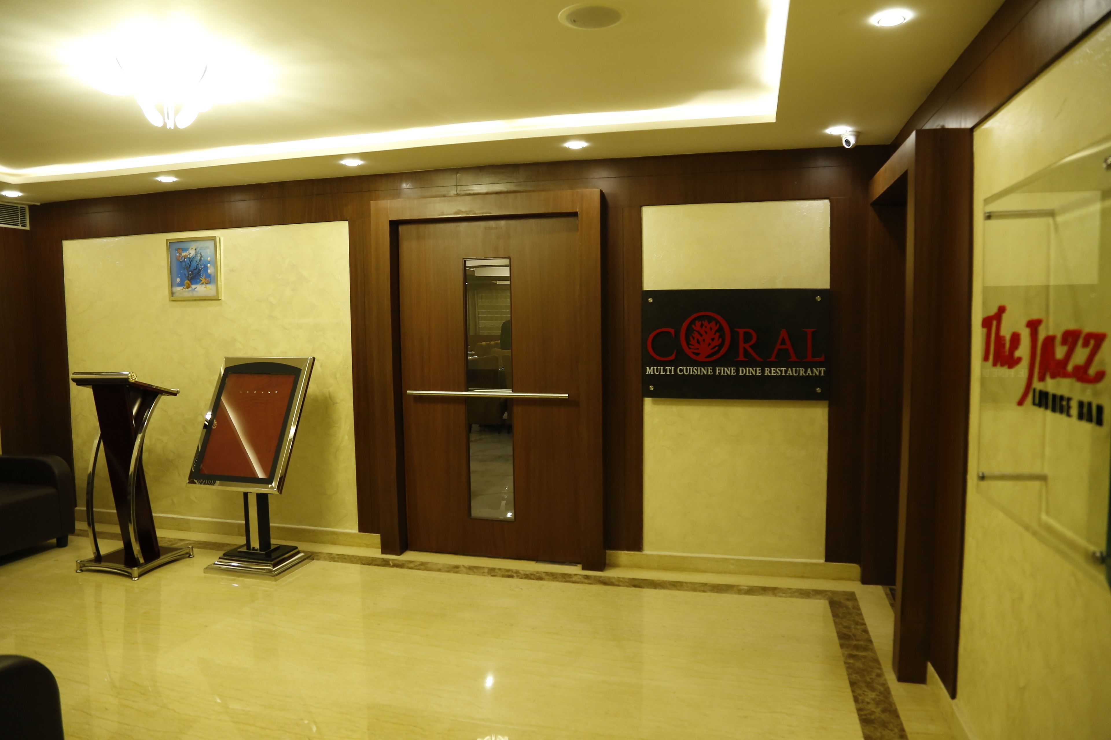 A lobby with a reception desk, a sign for Coral Fine Dining Restaurant, and The Jazz Lounge Bar.