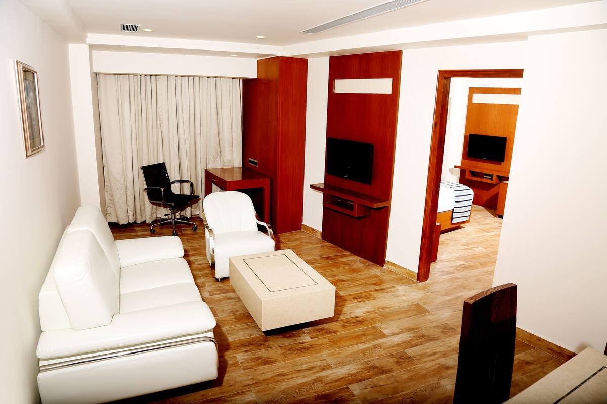 A modern living room with a white sofa, a small table, a TV, and a wooden floor.