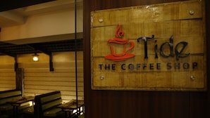 Un letrero de madera con un logotipo de taza de café y el texto "Tide The Coffee Shop".