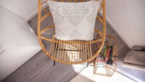 A wicker chair with a patterned cushion in a room with wooden flooring and white walls. - Suites del Arenal Olehousing (Seville)