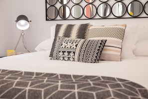 A neatly made bed with patterned pillows and a geometric throw blanket. - Suites del Arenal Olehousing (Seville)