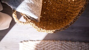 Un panier tressé doté d’une anse, posé sur une surface en bois.