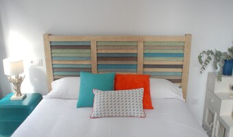 A bed with white bedding, a wooden headboard with horizontal slats, and colorful pillows.