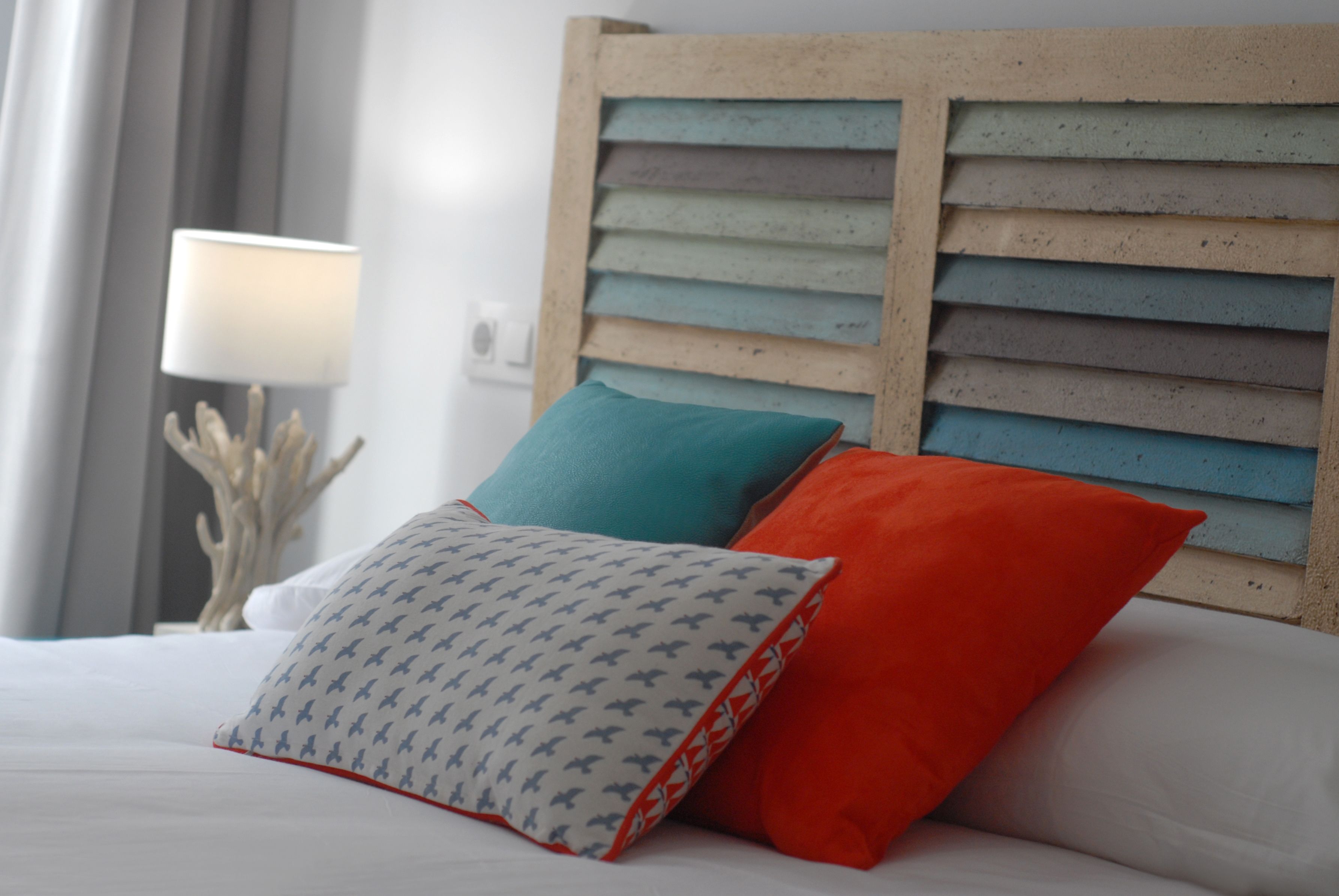 A bed with two pillows, one with a pattern and one solid color, and a wooden headboard.