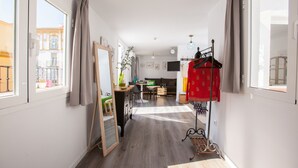 A bright, well-lit hallway with a dining area, a mirror, and a coat rack. - Suites del Arenal Olehousing (Seville)