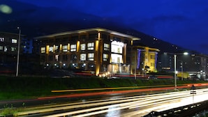 A building with multiple floors and balconies, surrounded by a road with light trails indicating traffic. - Tara Phendeyling Hotel (Thimphu)