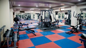 A gym with various exercise equipment, including dumbbells, a bench press, and cardio machines. - Tara Phendeyling Hotel (Thimphu)
