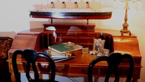A wooden desk with a model ship, books, a lamp, and decorative items.