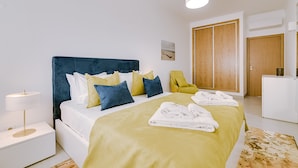 Ein modernes Schlafzimmer mit Bett, Nachttisch und einem Sessel.