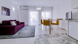 Ein modernes Wohnzimmer mit einem violetten Sofa, einem Esstisch mit gelben Stühlen und einem Flachbildfernseher.