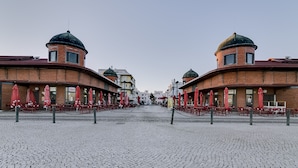 Eine Kopfsteinpflasterstraße mit Backsteingebäuden, die Kuppeldächer und Außenbereiche mit roten Sonnenschirmen aufweisen.