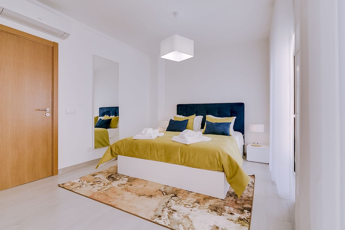 A modern bedroom with a bed, bedside table, and a large mirror.