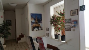 A hallway with a painting of the Eiffel Tower, a potted plant, and framed pictures on the wall.