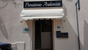 The exterior of a building with a sign reading "Pensione Ardienza." There are two signs on the wall, one with the logo "Albergo" and another with "Pubblio."