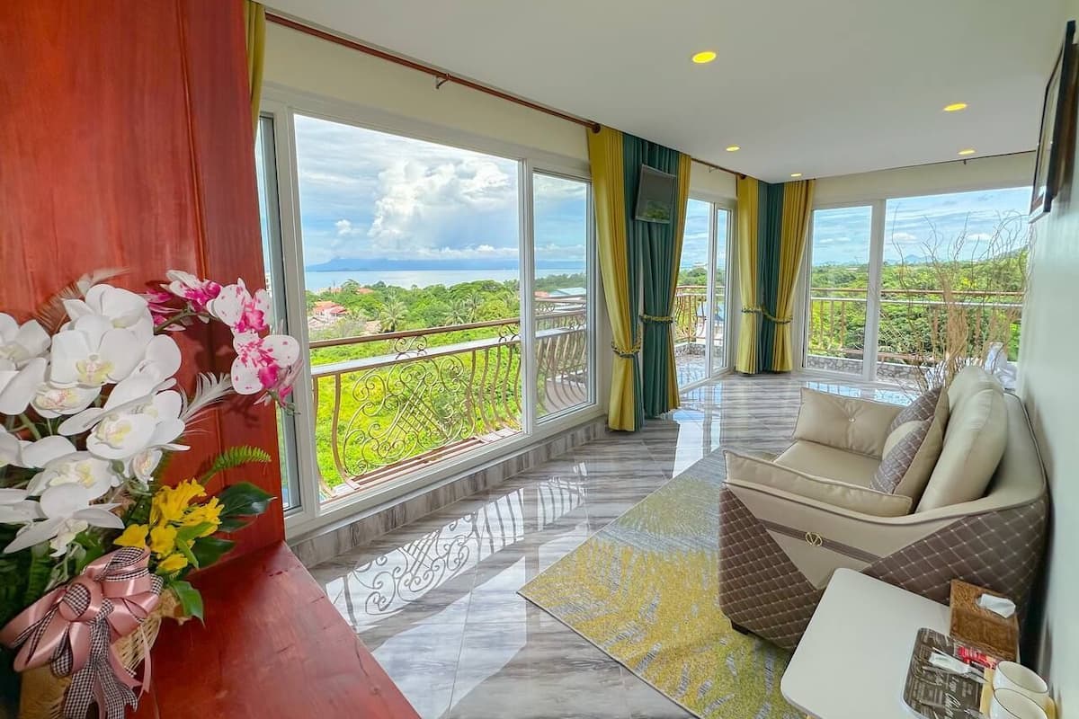 Un'ampia stanza con un balcone, ampie finestre e vista sul verde.