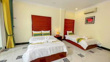 A hotel room with two beds, a nightstand, a lamp, and a window with curtains.
