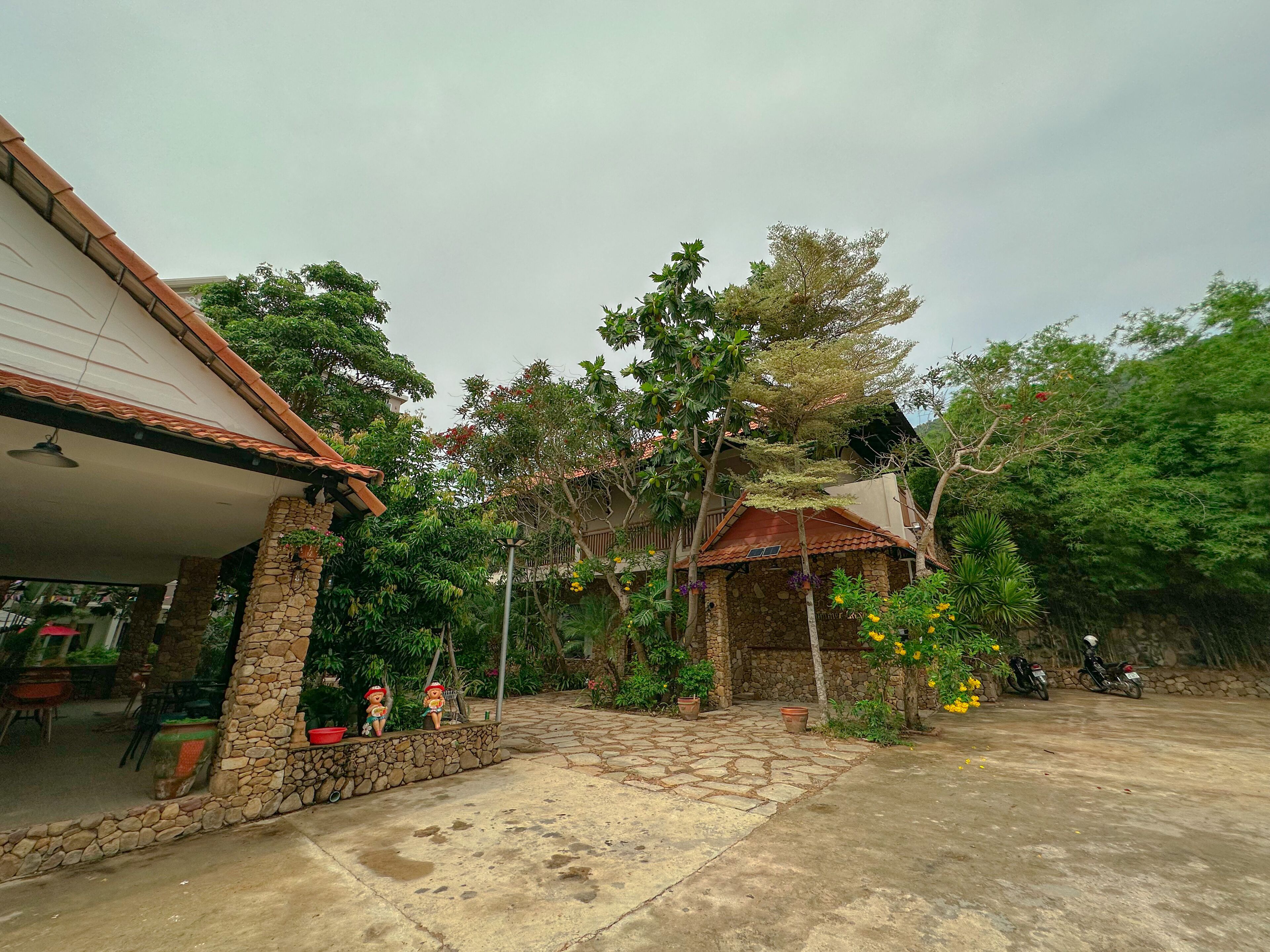 A courtyard with stone walls, potted plants, and a covered seating area.