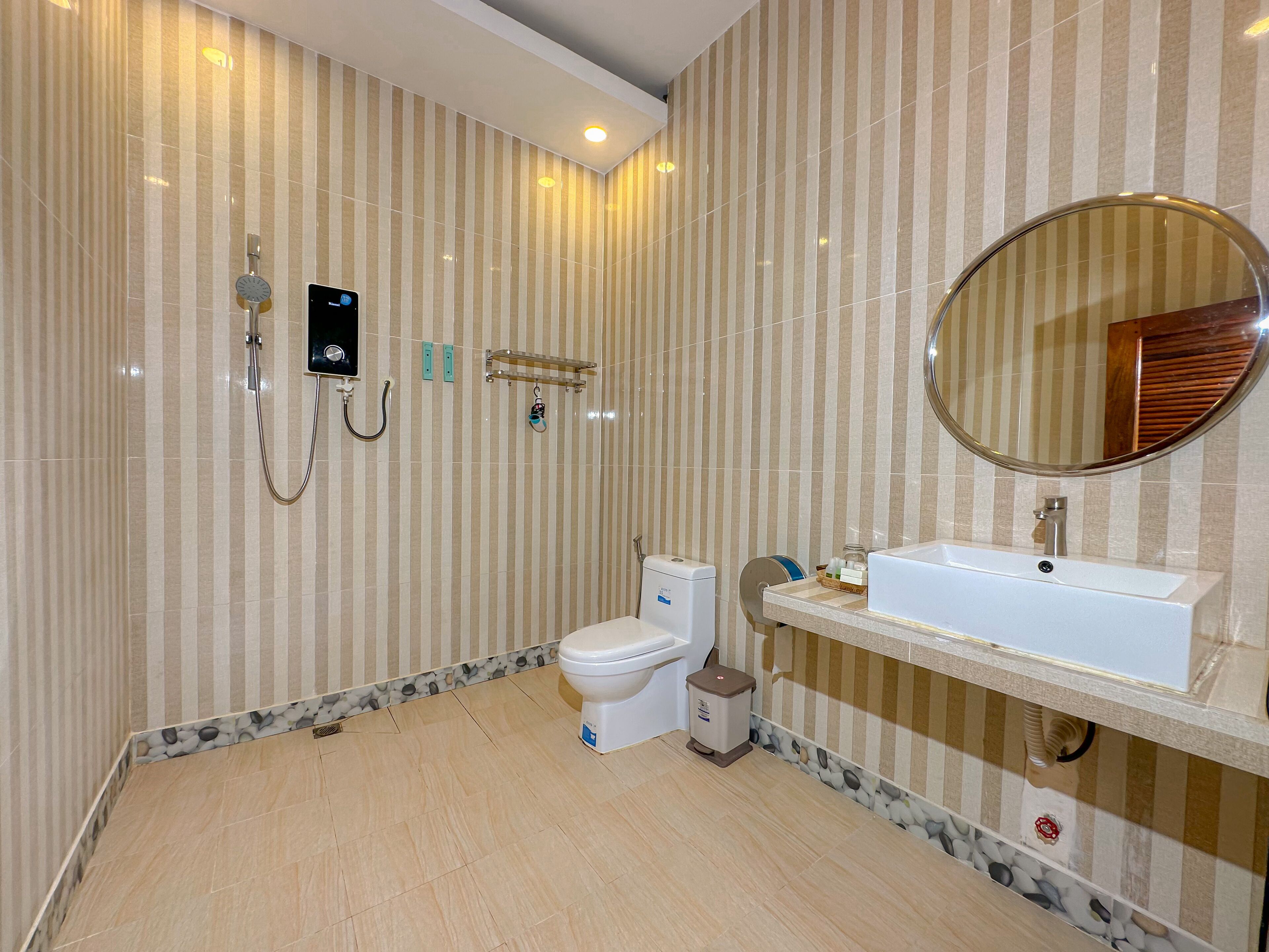 Un baño con paredes a rayas, un inodoro, un lavabo y una ducha.