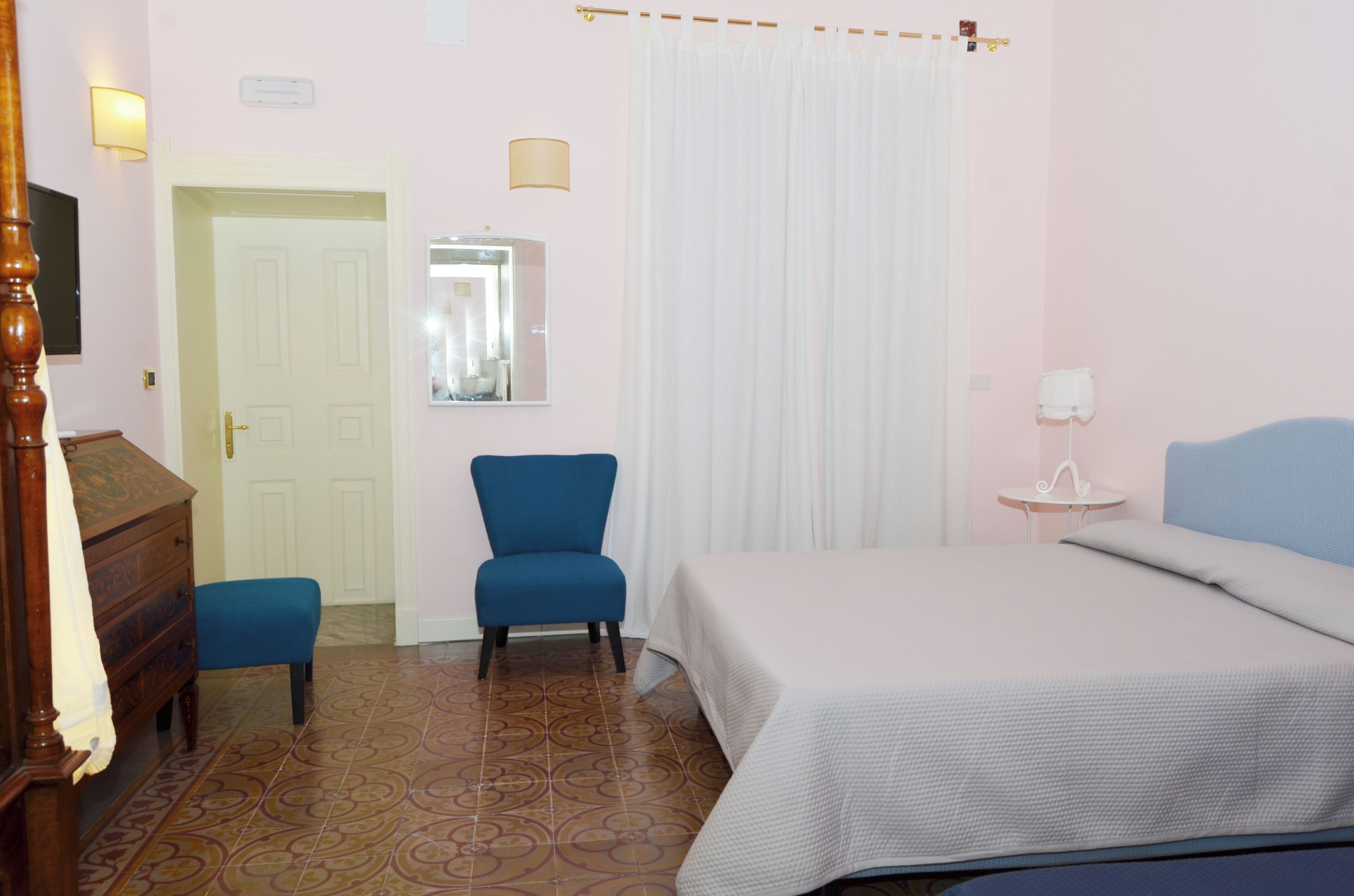 A bedroom with a bed, a chair, a dresser, a mirror, and a small table.