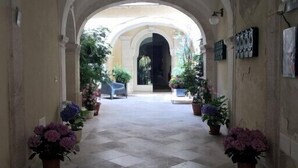 Un pasillo con arcos, plantas en macetas y suelo de baldosas.
