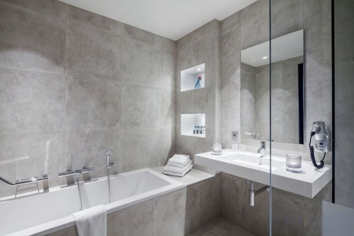 A modern bathroom with a bathtub, a vanity with a mirror, and a hairdryer.