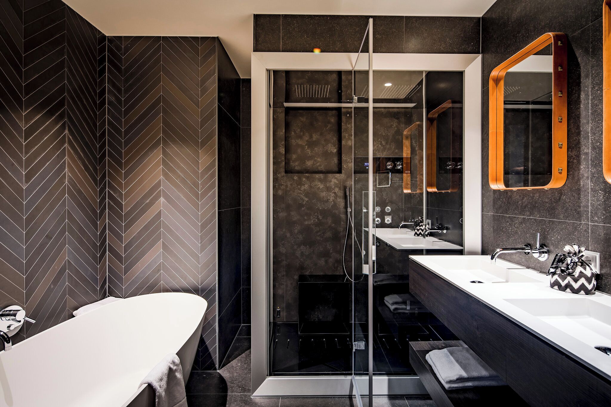 A modern bathroom with a large mirror, two sinks, and a shower enclosure.