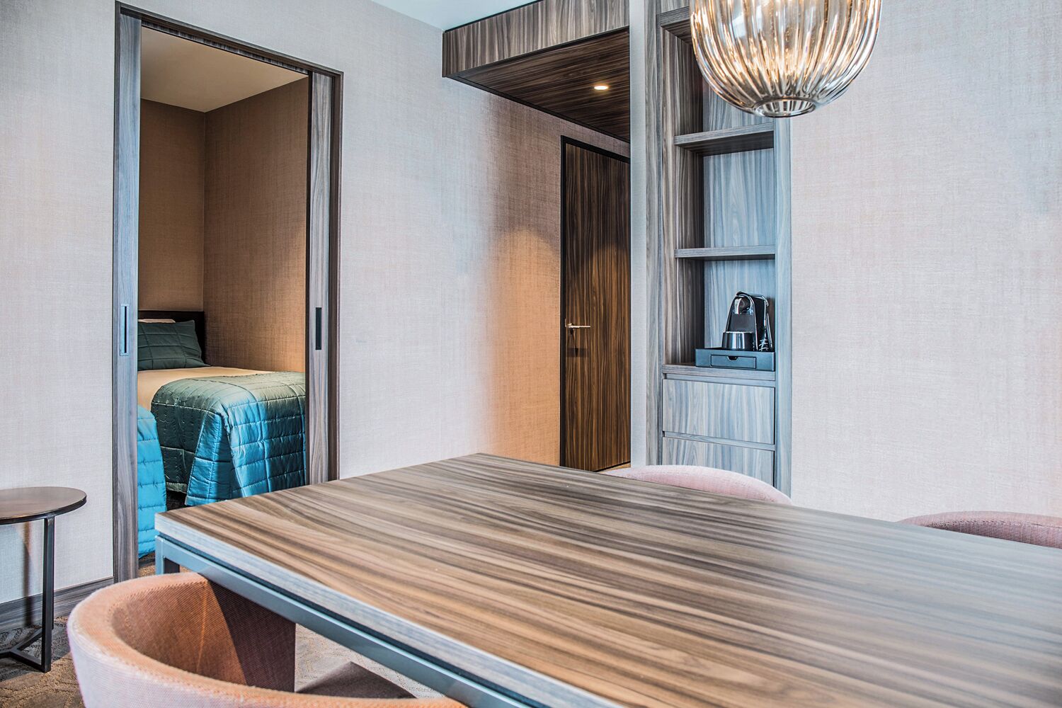 A modern bedroom with a bed, a desk, a chair, and a wardrobe.