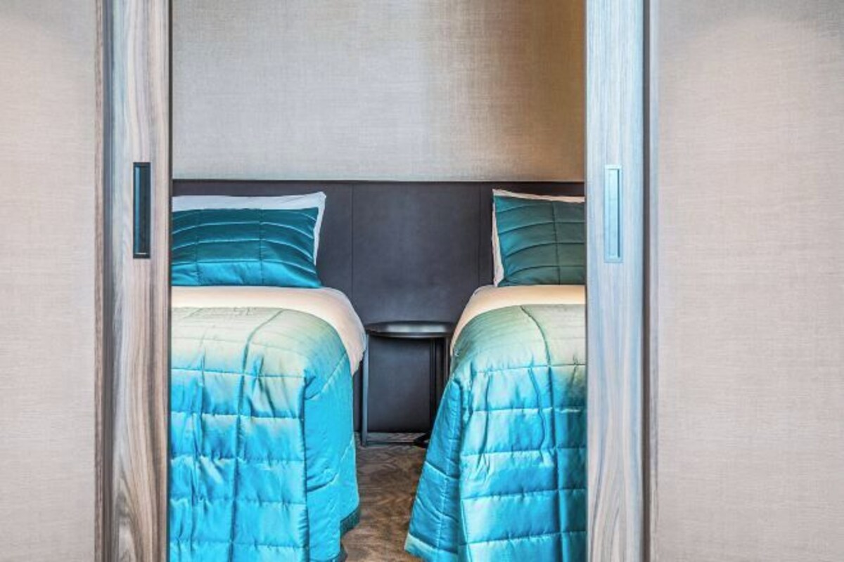 A room with two beds, a dark headboard, and a small table.