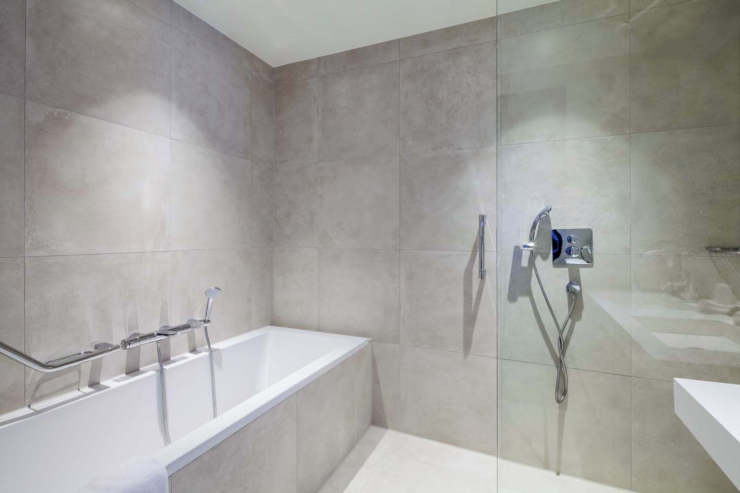 Un baño moderno con bañera, ducha y panel de control en la pared.