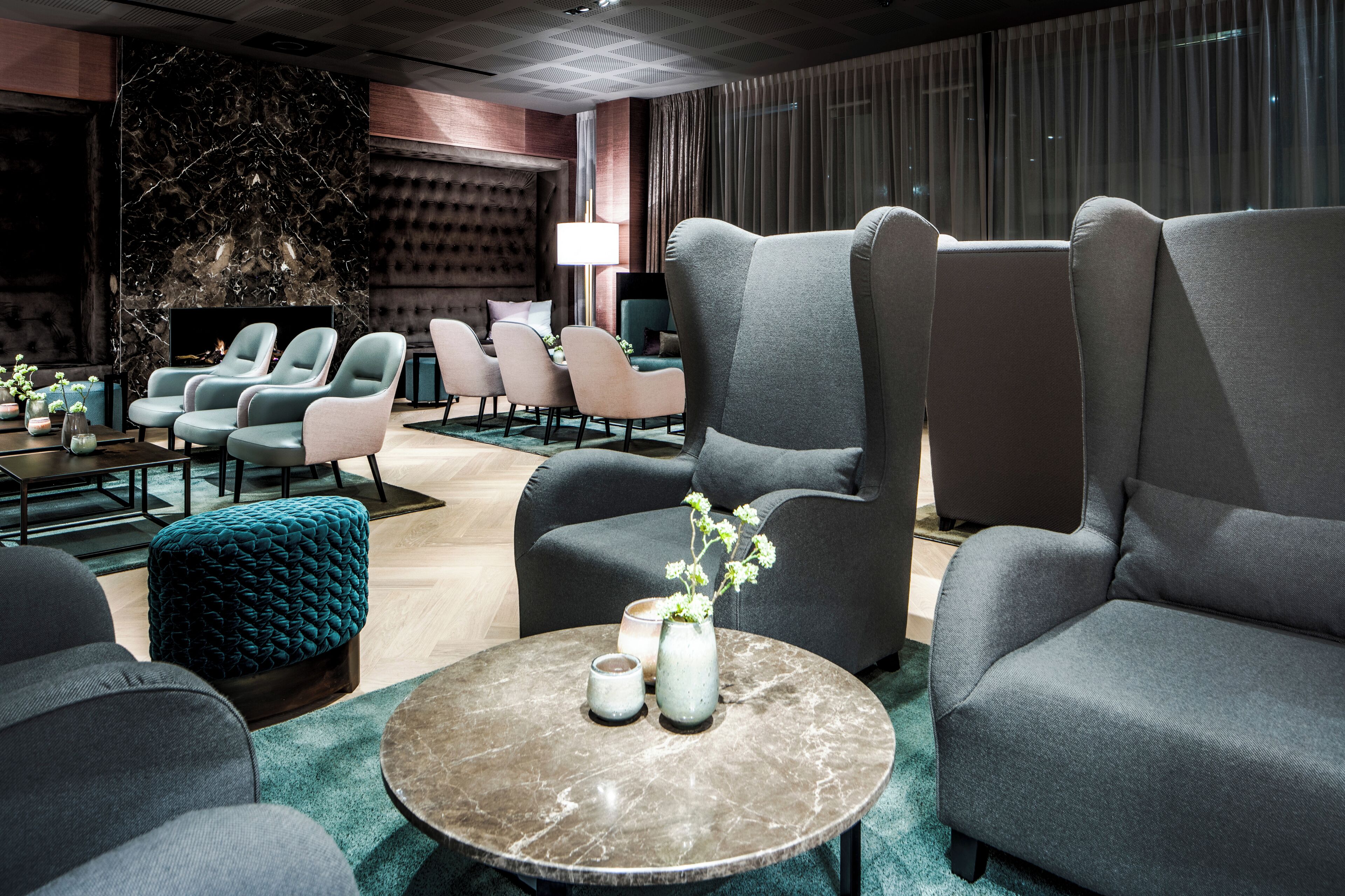 Ein moderner Lounge-Bereich mit Sitzgelegenheiten, einem Marmor-Couchtisch und einer Wand mit strukturierter Oberfläche.