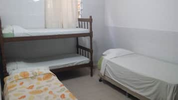 Simple, compact room with a bunk bed arrangement and a window with sheer curtains.