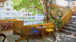 An outdoor seating area with bamboo fencing, a tree, and a staircase. - Icarai Suites (Niteroi)