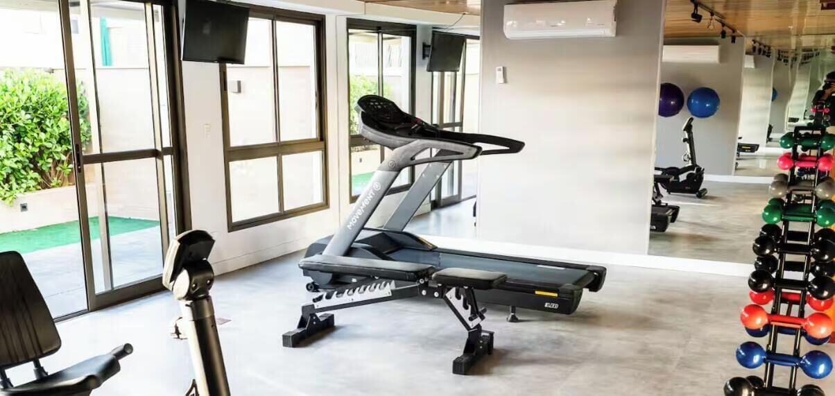 A gym with exercise equipment, including a treadmill and weightlifting stations.