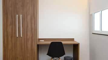 Una habitación con un armario de madera, un escritorio y una silla negra.