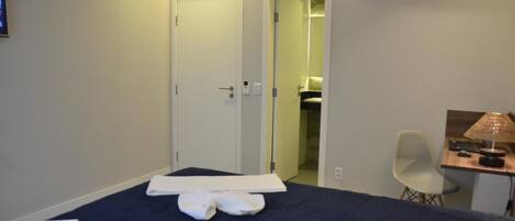 Une chambre d’hôtel équipée d’un lit, d’un bureau avec une lampe, d’une chaise et d’un appareil de climatisation.