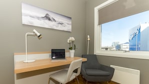 Un espacio de oficina moderno con un escritorio, una computadora portátil, dos sillas, una orquídea en maceta y una ventana con vista a la ciudad.