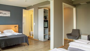 A hotel room with a bed, a chair, a wardrobe, and a bathroom.