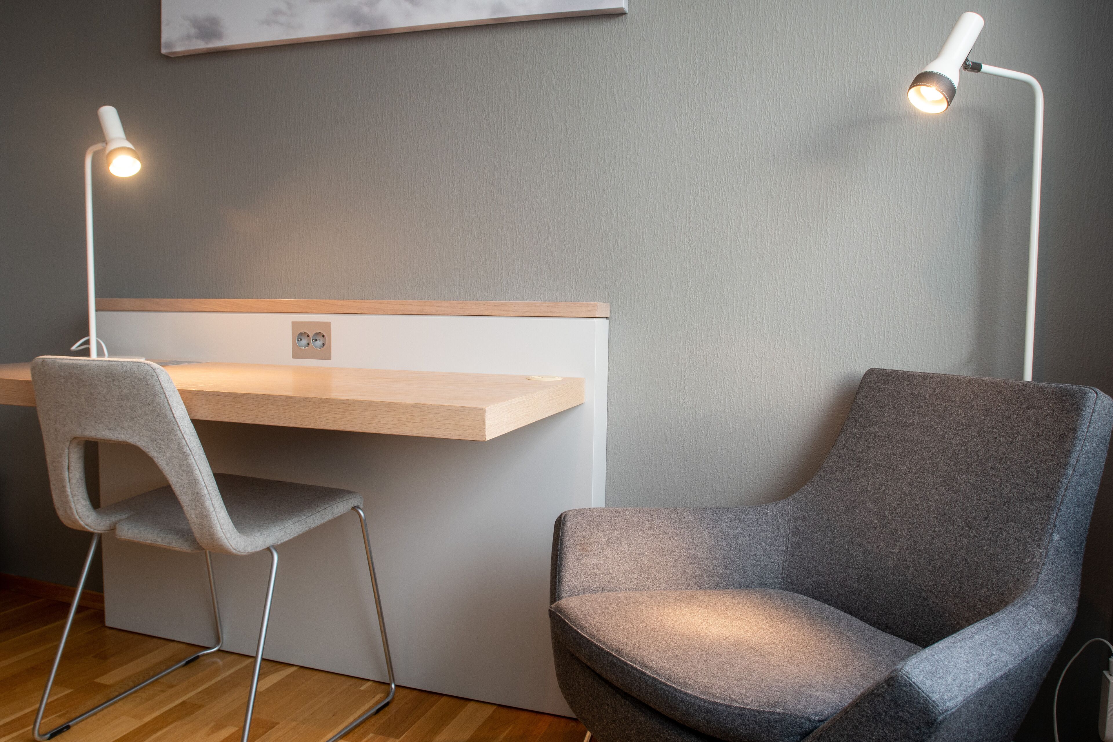 Een moderne kantoorruimte met een bureau, twee stoelen en twee staande lampen.
