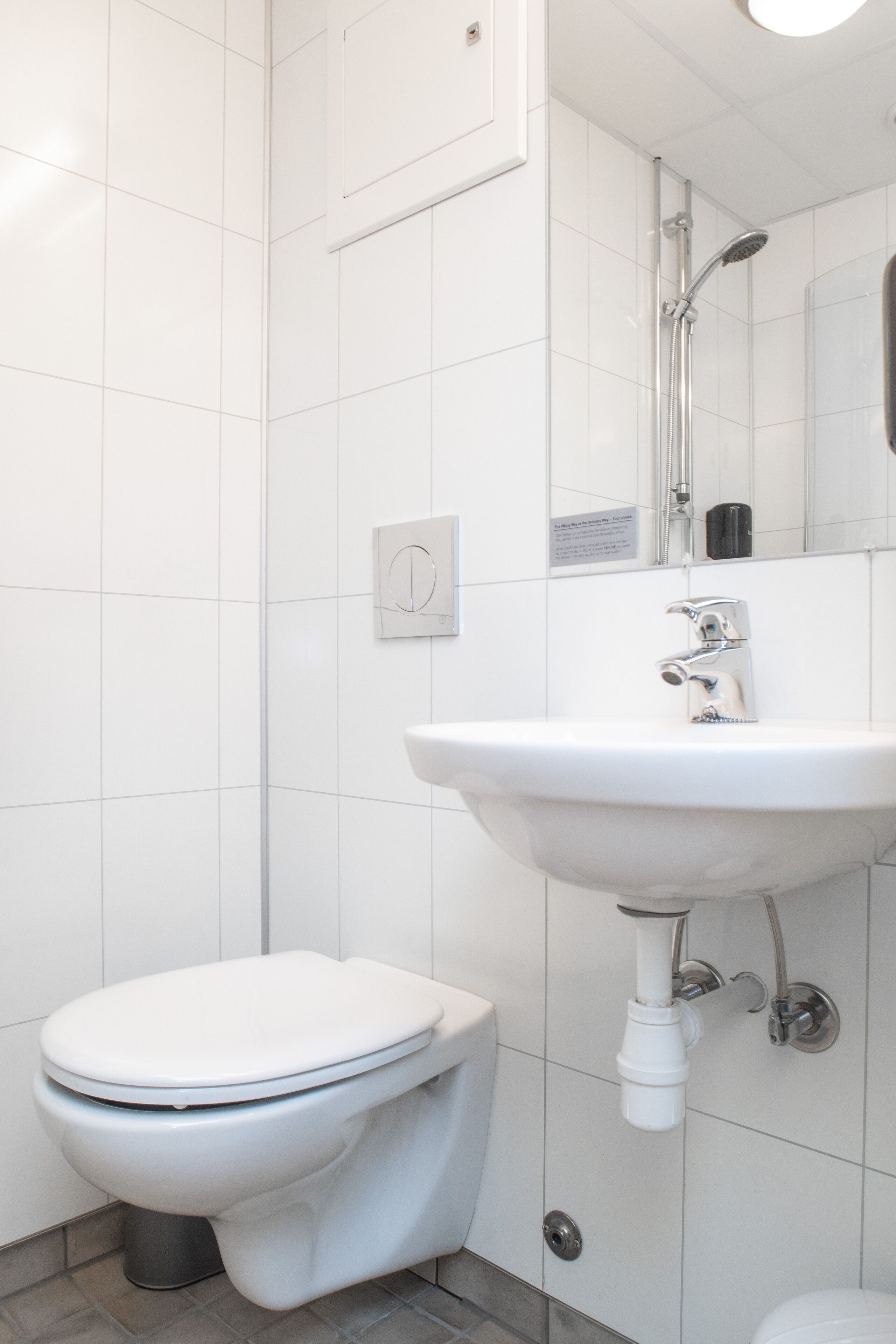 Et moderne badeværelse med toilet, vask og bruser.