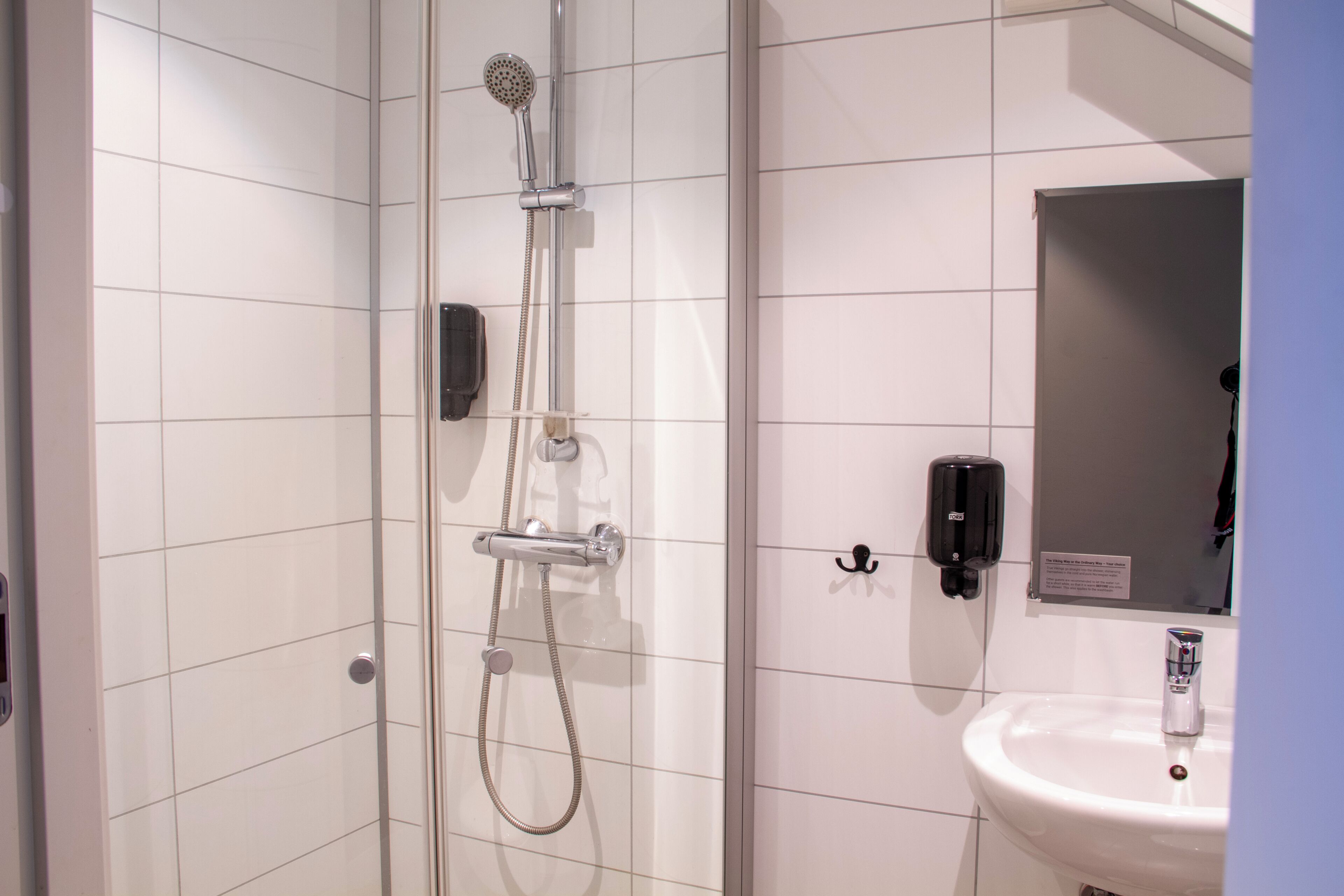 A bathroom with a glass-enclosed shower, a white sink, and a mirror.