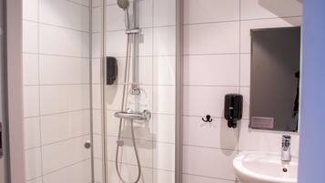 A bathroom with a glass-enclosed shower, a white sink, and a mirror.