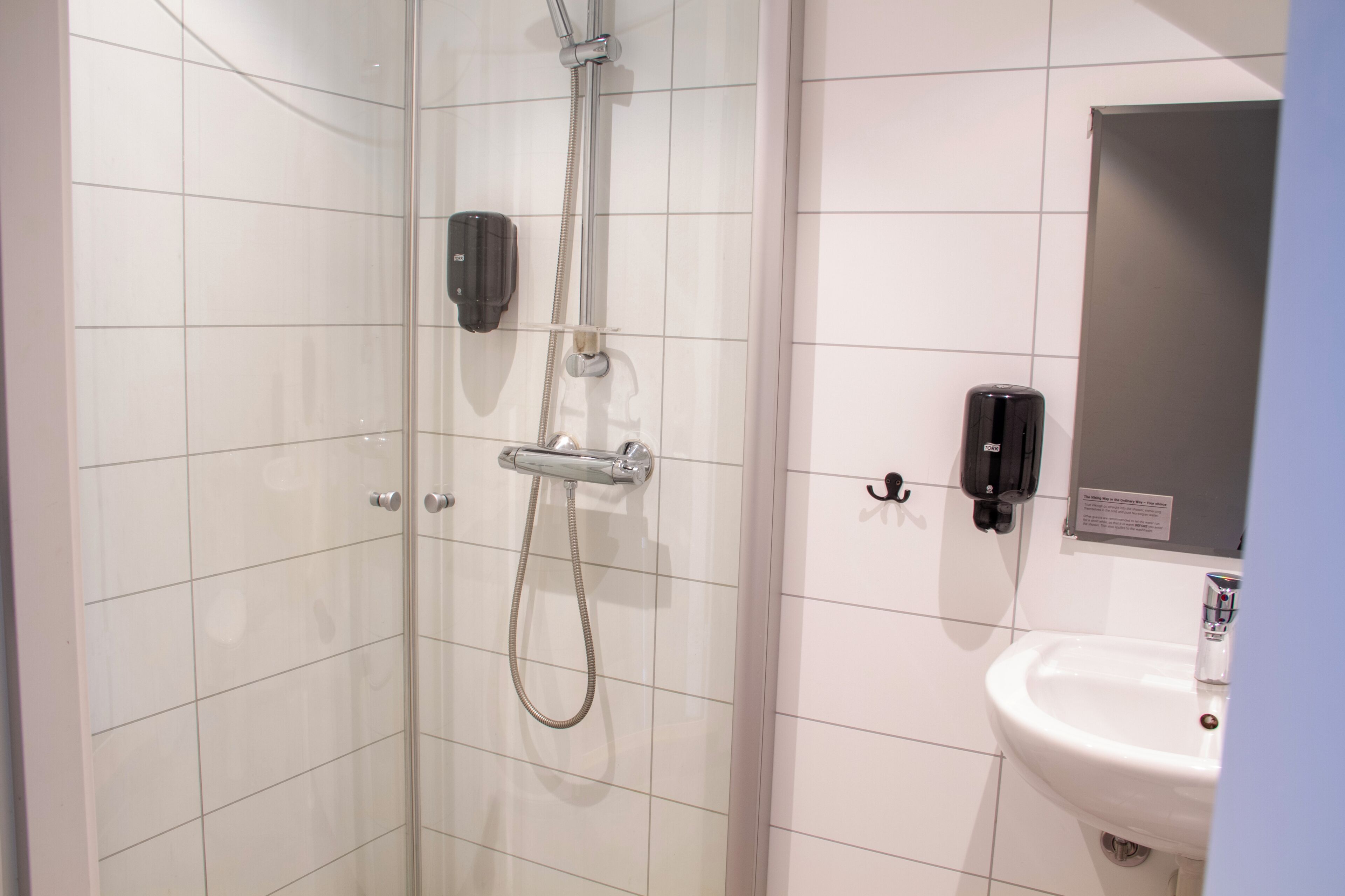 A bathroom with a glass shower enclosure, a white sink, and a mirror.