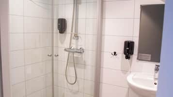 A bathroom with a glass shower enclosure, a white sink, and a mirror.