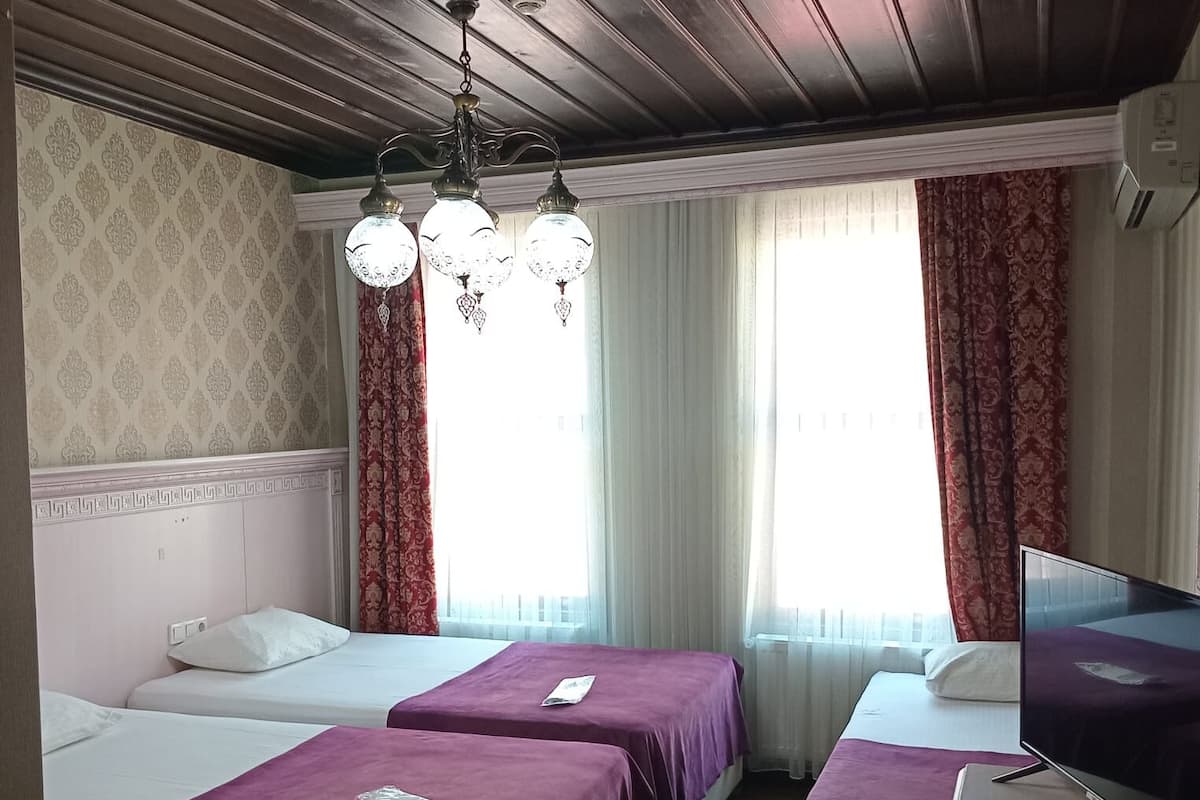 A hotel room with two beds, a TV, and a desk with a remote control.
